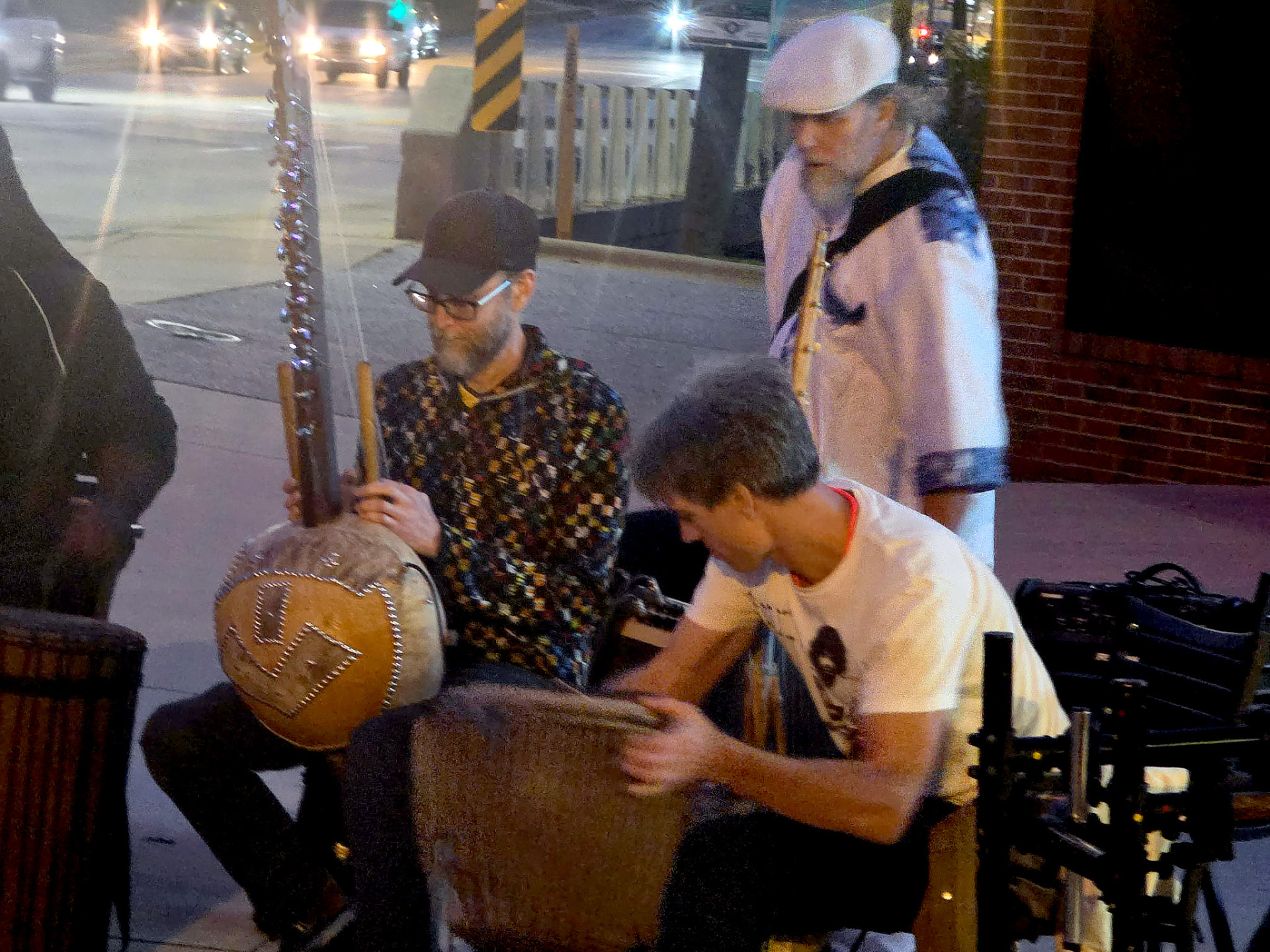 Musicians with kora and drums outside at night