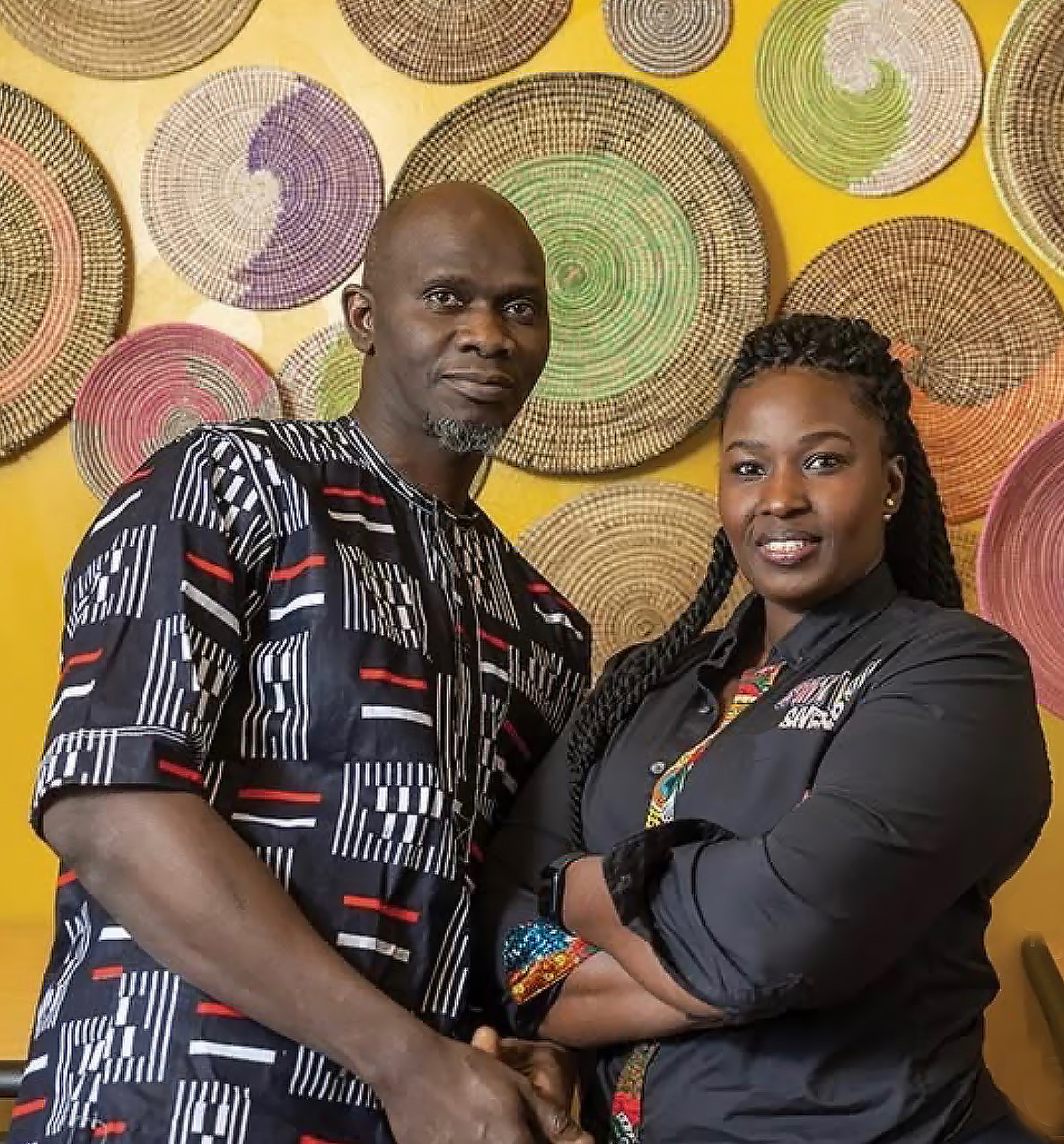 The owners of Saint Louis Saveurs in front of woven basket art